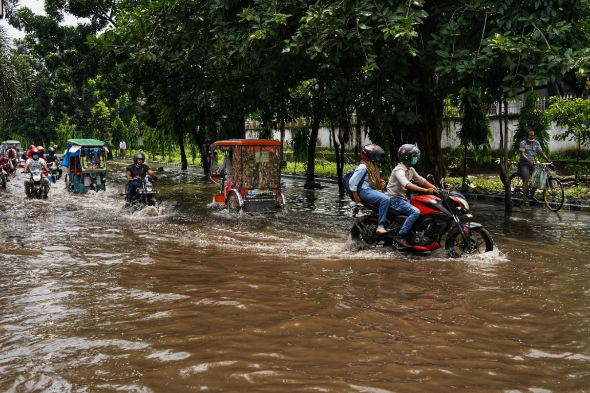 people riding motorcycles through flooded street